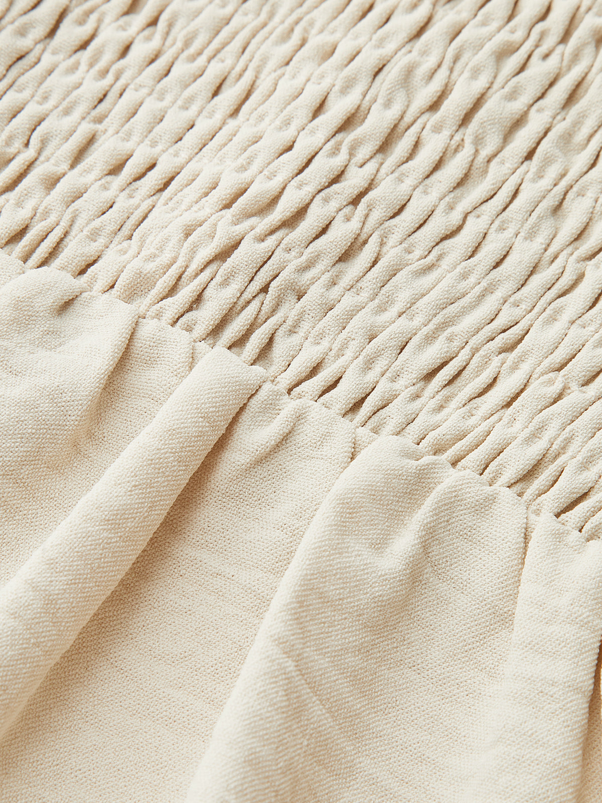 Sleeveless beige maxi dress with contrast wavy trim, gathered top, and pleated skirt.