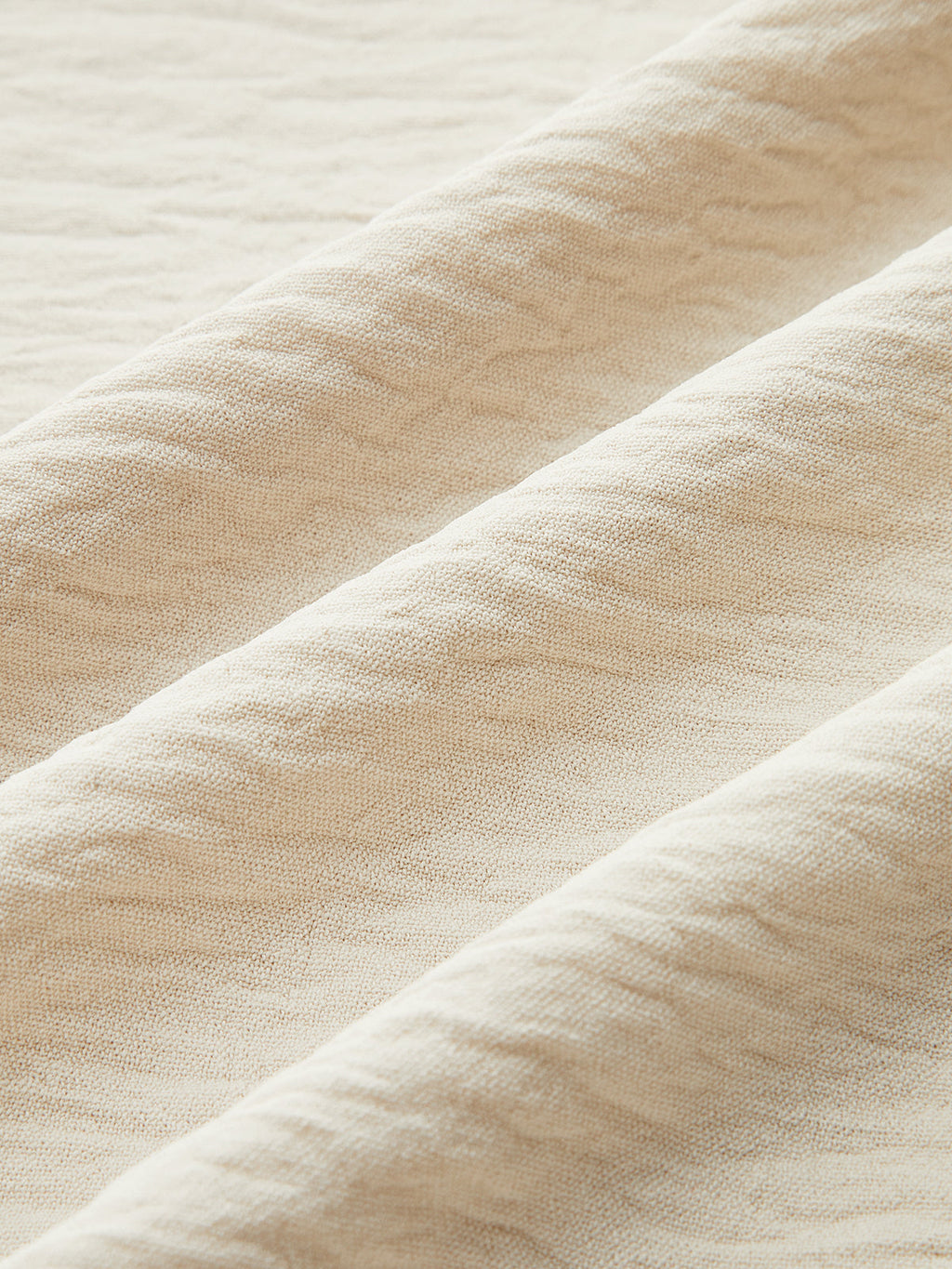 Soft, textured beige maxi dress with gentle folds and distinct wavy contrast trim detailing.