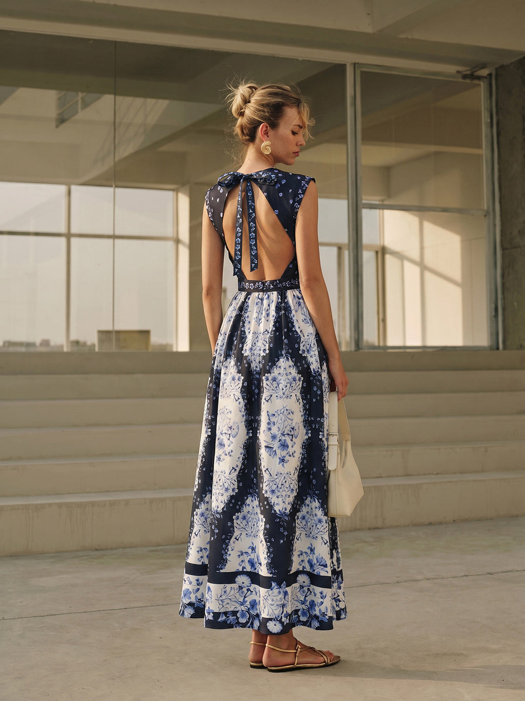 A backless maxi dress with floral patterns, featuring an open back and bow detail.