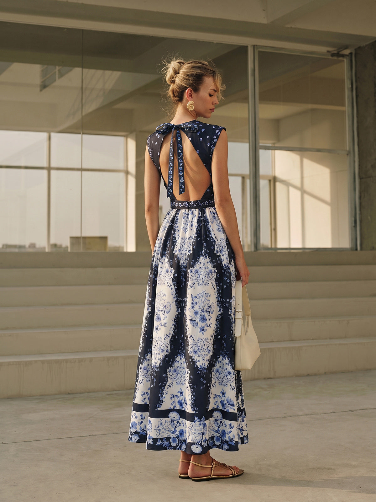 A backless maxi dress with floral patterns, featuring an open back and bow detail.