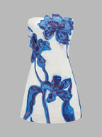 A white strapless mini dress with blue floral prints and 3D flower appliqué details.