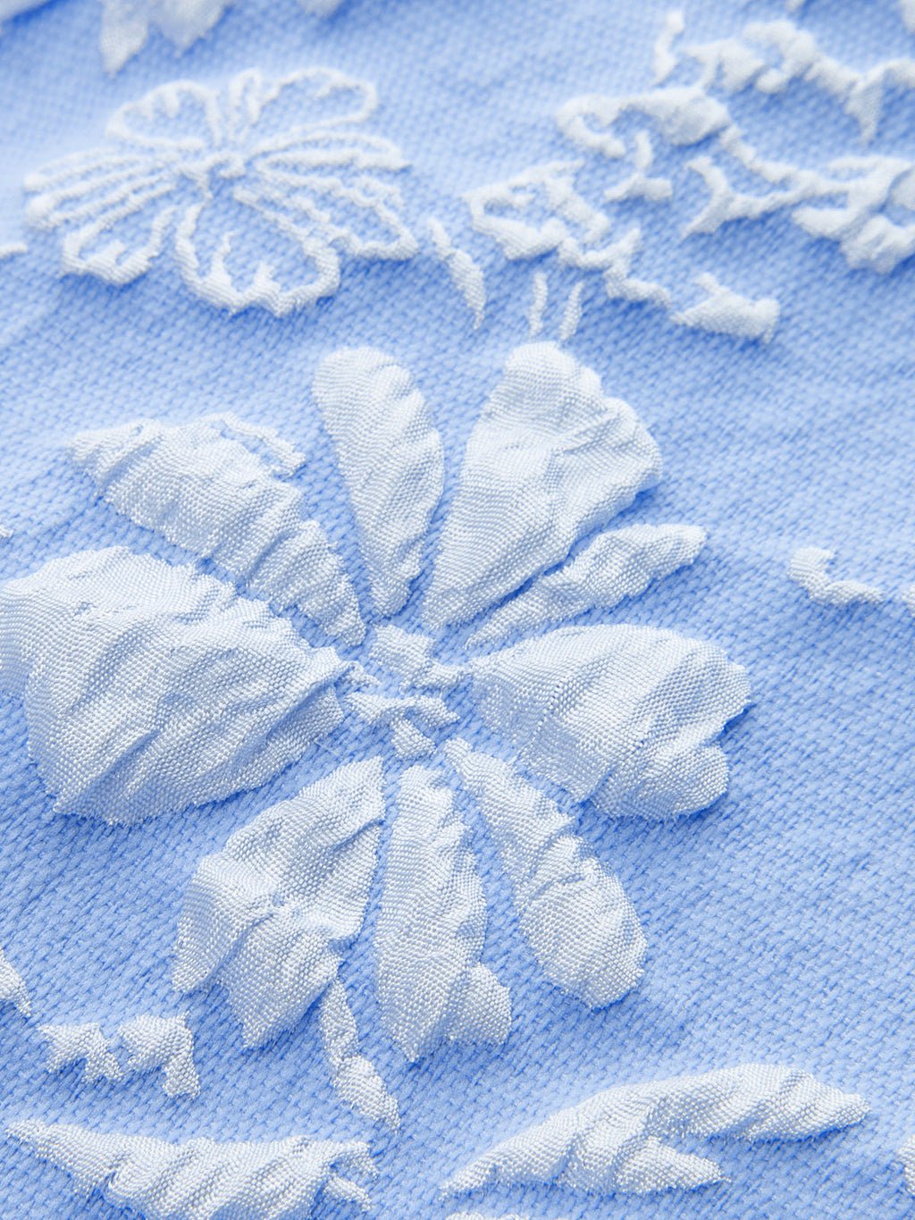 Sleeveless Jacquard mini dress in light blue with delicate white embroidered floral patterns.