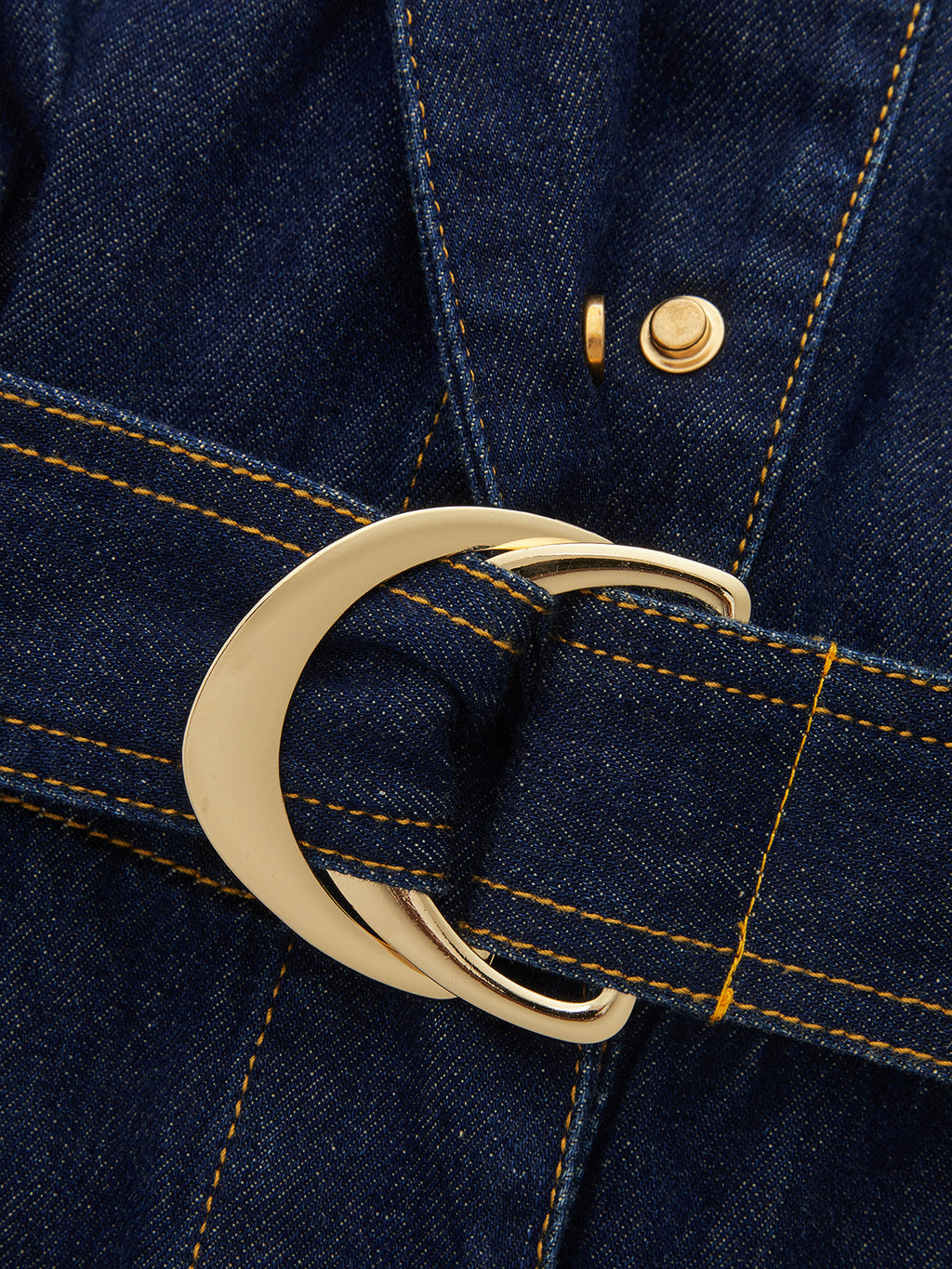 Sleeveless denim romper with gold buckle, yellow stitching, and epaulet details on the belt.