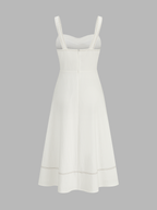 White sleeveless midi dress with contrast stitching, square neckline, fitted bodice, flared skirt.