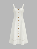 A midi dress with a square neckline, thick straps, gold buttons, and contrast tan stitching.
