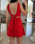 A square neck romper with thick straps, textured fabric, and a tie-back skort design.
